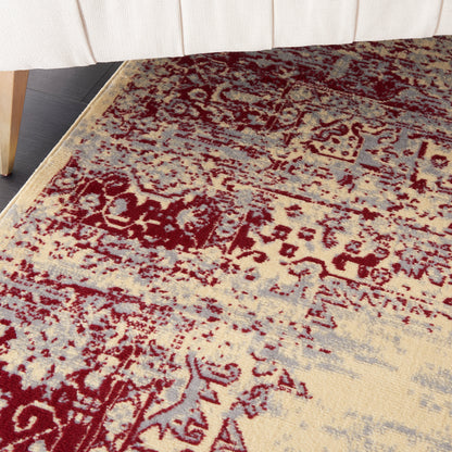 Beige oriental rug with burgundy floral medallion pattern, distressed blue-gray accents, low-pile under a light sofa.