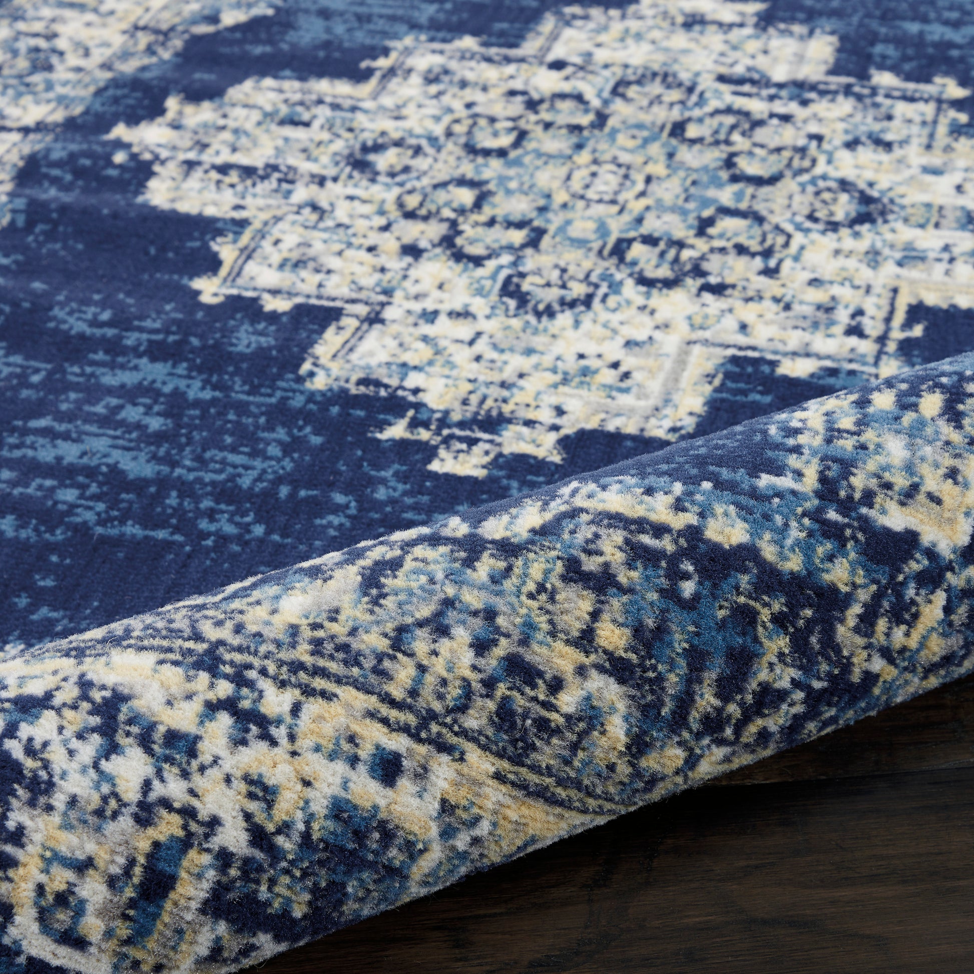 Navy blue distressed oriental rug with cream motifs; soft woven texture & rolled edge.