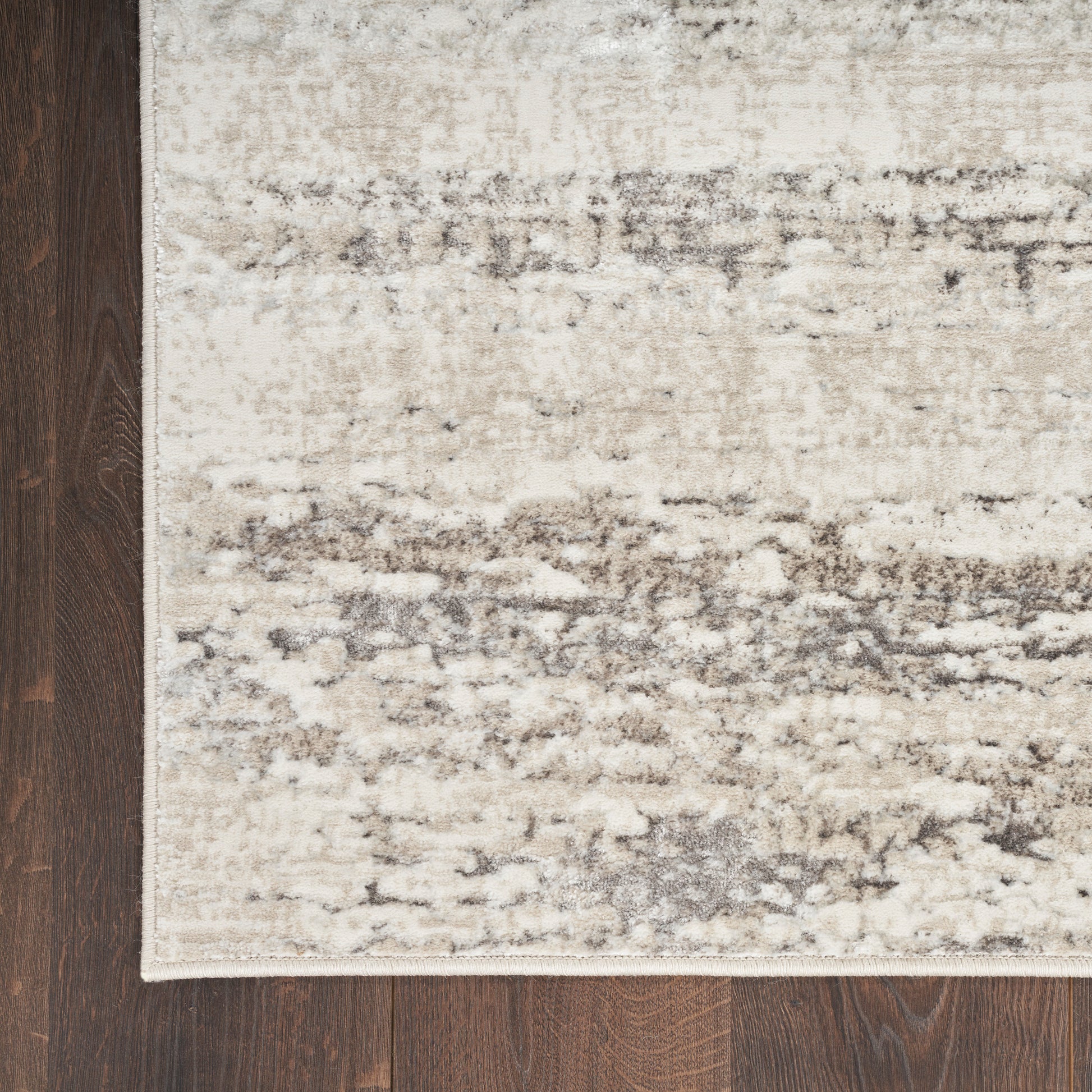 Beige distressed area rug with abstract gray pattern on dark wood floor.
