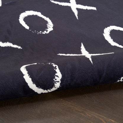 Navy rug with white abstract brushstroke circles and crosses on a dark wood floor