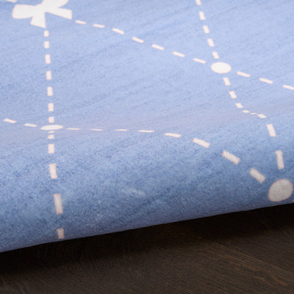 Soft blue fabric with white dashed-line grid pattern, folded over a dark wooden surface.
