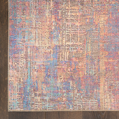 Abstract geometric area rug in peach, blue and lavender with distressed texture on a wooden floor.