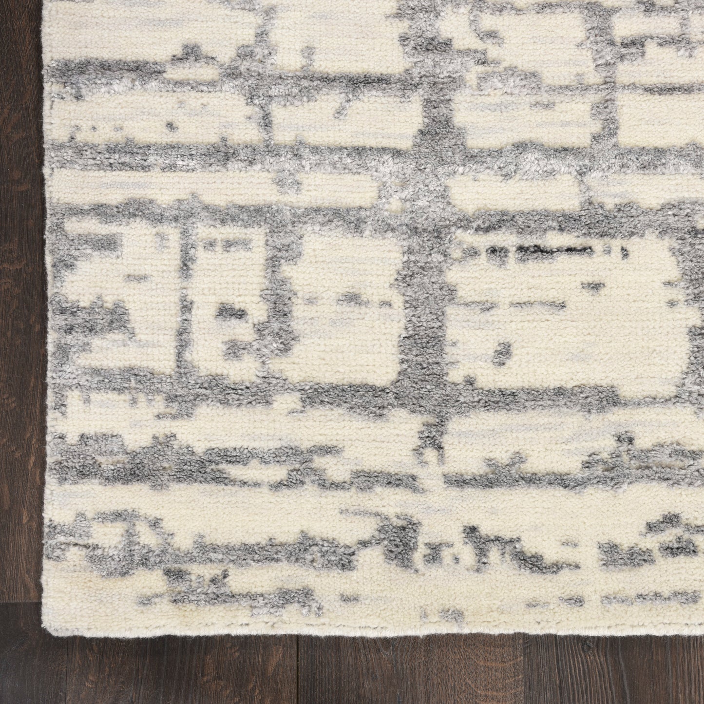 Cream & gray distressed abstract patterned rug with blocky shapes on hardwood floor.