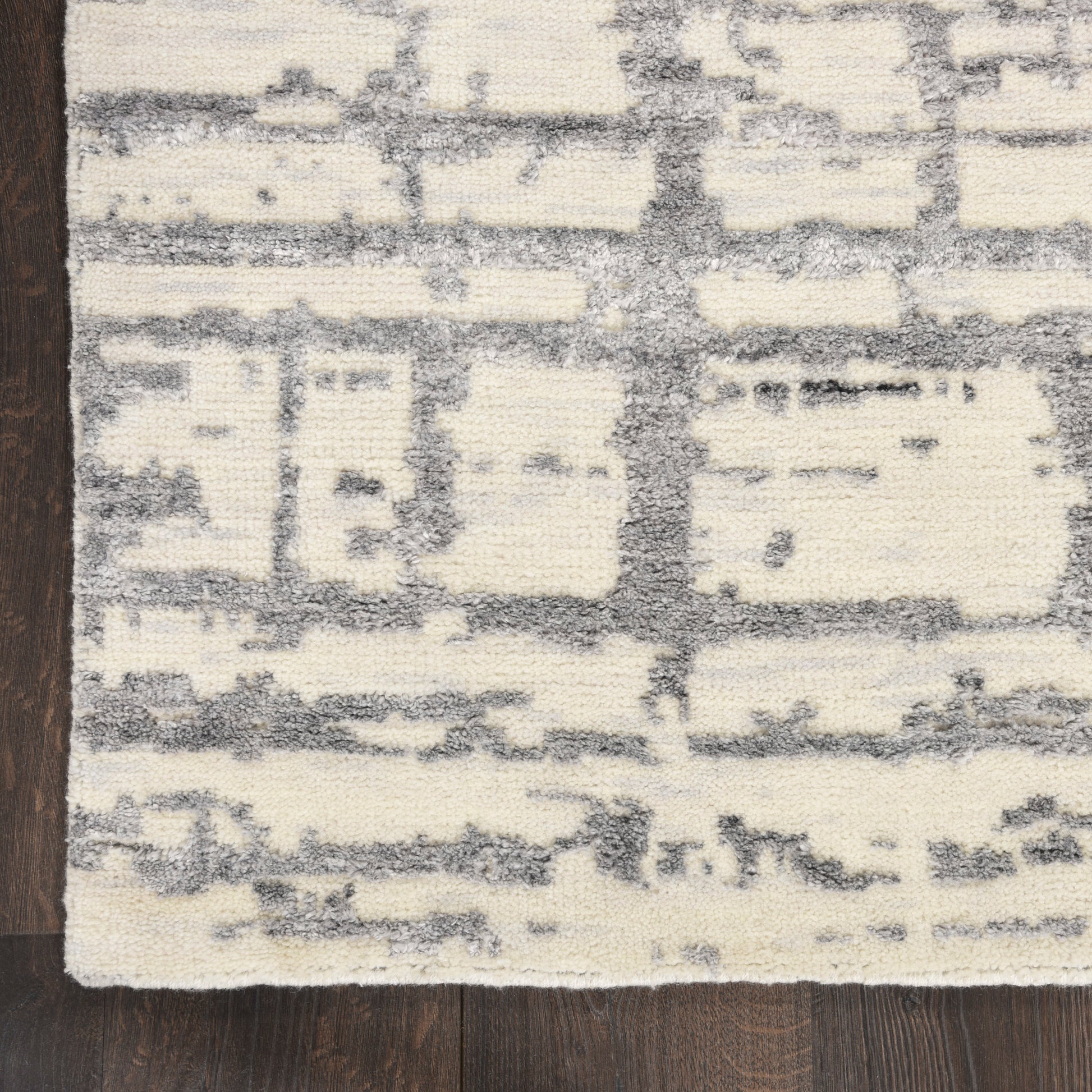 Cream & gray distressed abstract patterned rug with blocky shapes on hardwood floor.