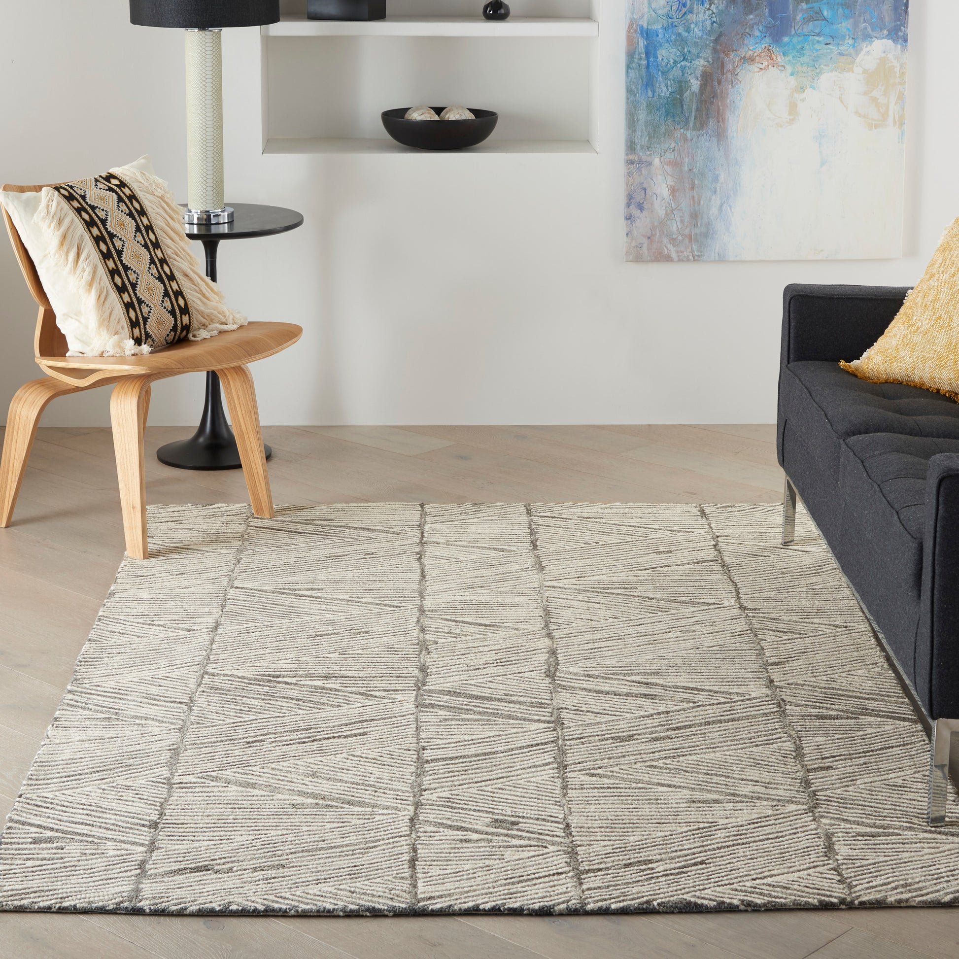 Beige textured area rug with diagonal geometric lines in a modern living room, 4' x 6' size, beside a black sofa and a wooden chair.