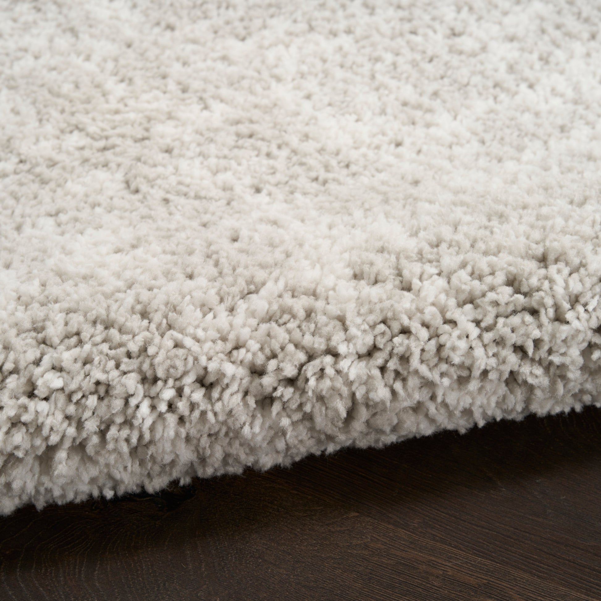 Cream shag area rug with dense plush pile on dark wood floor.