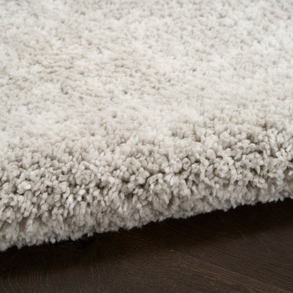 Cream shag area rug with dense plush pile on dark wood floor.