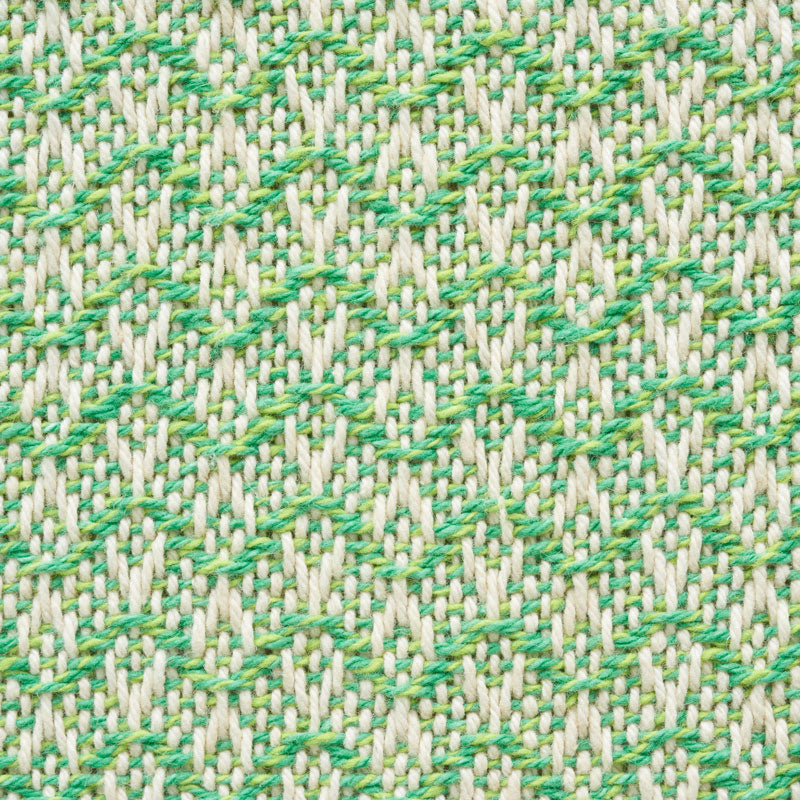 Close-up of beige woven fabric with a bright green leaf pattern; textured upholstery fabric.