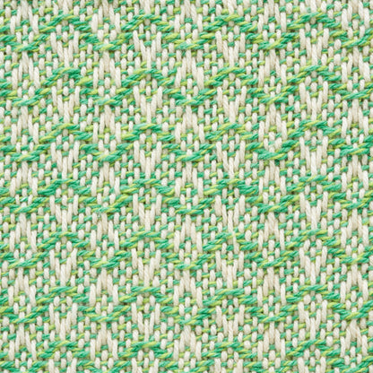 Close-up of beige woven fabric with a bright green leaf pattern; textured upholstery fabric.