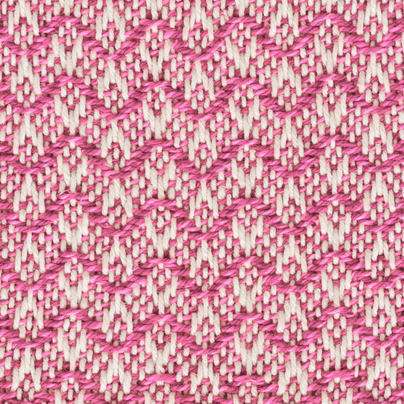 Close-up of magenta and cream woven fabric with zigzag chevron pattern, textured cotton-like textile.