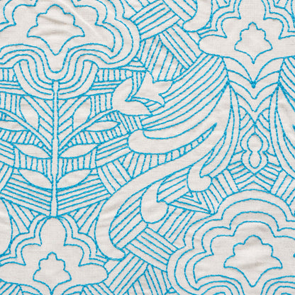 Teal blue embroidered pattern on light fabric; cloud and leaf motifs with geometric lines; decorative textile.