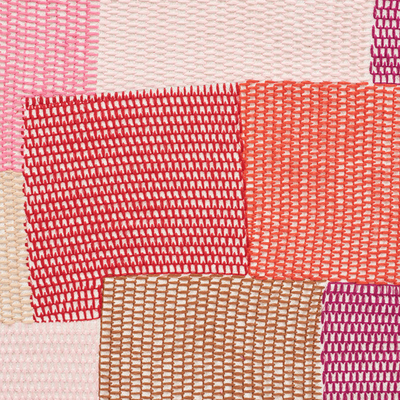 Colorful patchwork embroidery with pink, red, orange, beige and purple blocks in a textured pattern.