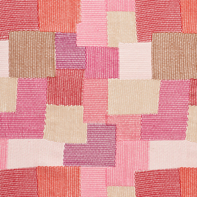 Patchwork fabric squares in pinks, reds, peaches and beiges; quilt-style textile for home decor.