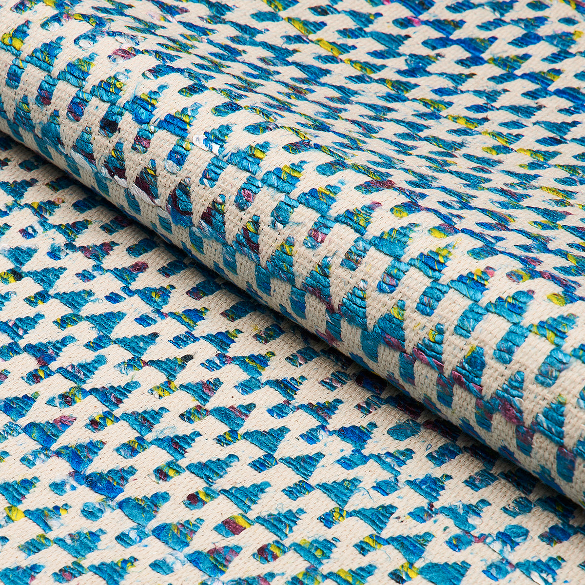 Rolled woven textile with blue geometric pattern on ivory base; teal, yellow and red specks; upholstery swatch.