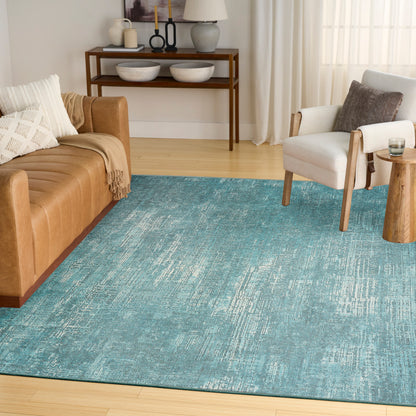 Blue distressed-textured area rug in a modern living room with tan leather sofa, white armchair, and wooden accents.