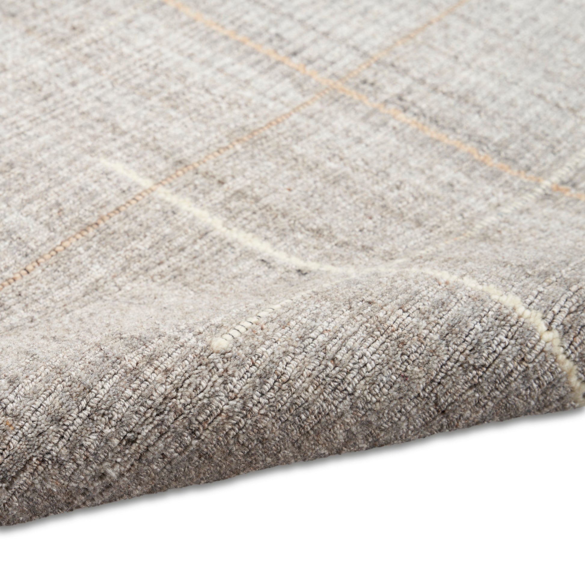 Beige-gray woven rug with subtle tan grid lines and a folded corner.