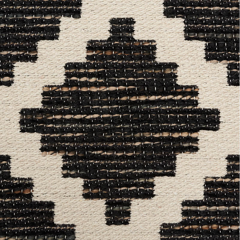 Woven rectangular area rug with black geometric diamond motifs on natural beige background; tribal pattern.