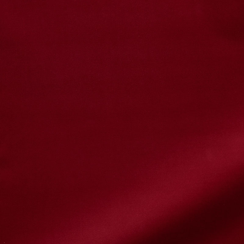 Deep red velvet fabric with a soft texture and a diagonal shadow across the surface.