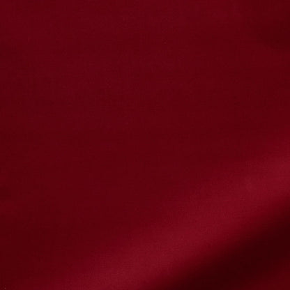 Deep red velvet fabric with a soft texture and a diagonal shadow across the surface.