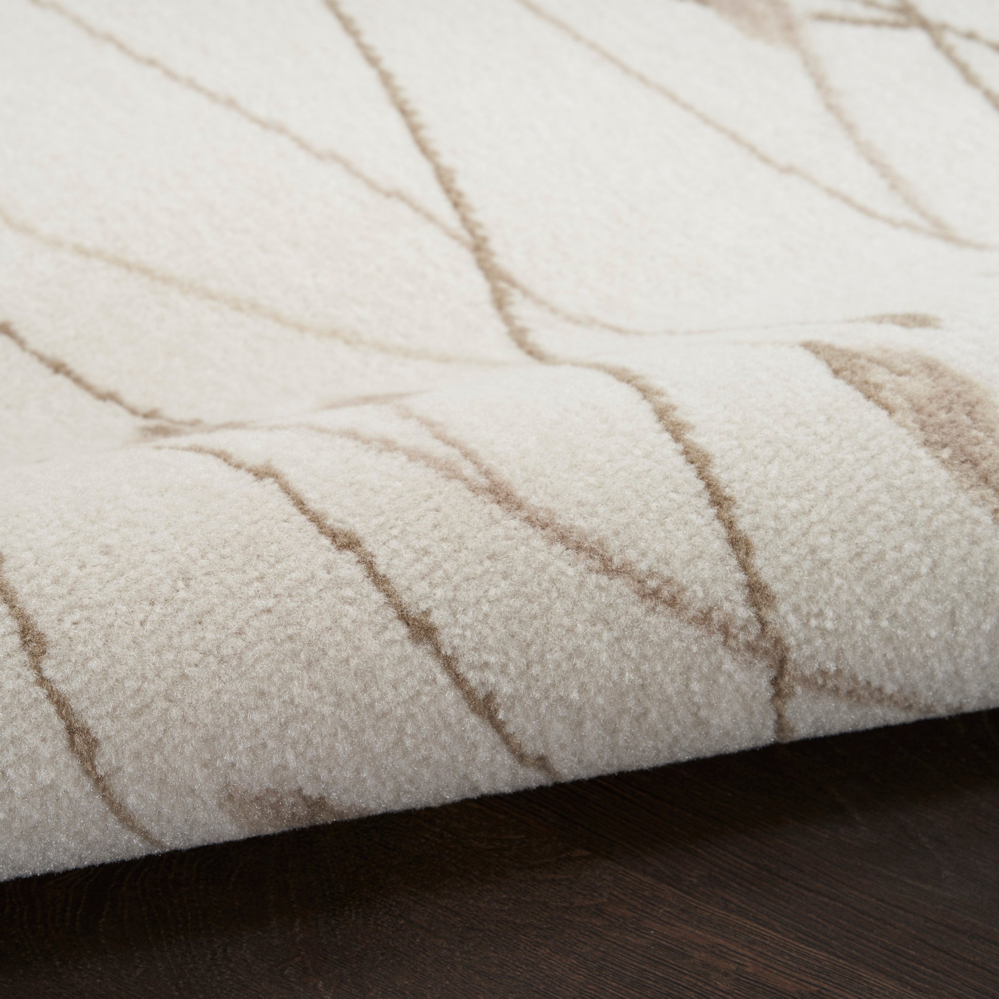 Cream shag rug with taupe wavy lines and plush textured pile on dark wood floor.