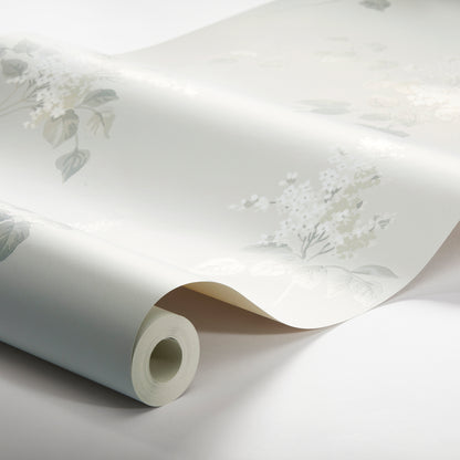 Rolled pale blue wallpaper with soft white floral botanical pattern, partially unrolled to show delicate leaves and flowers.