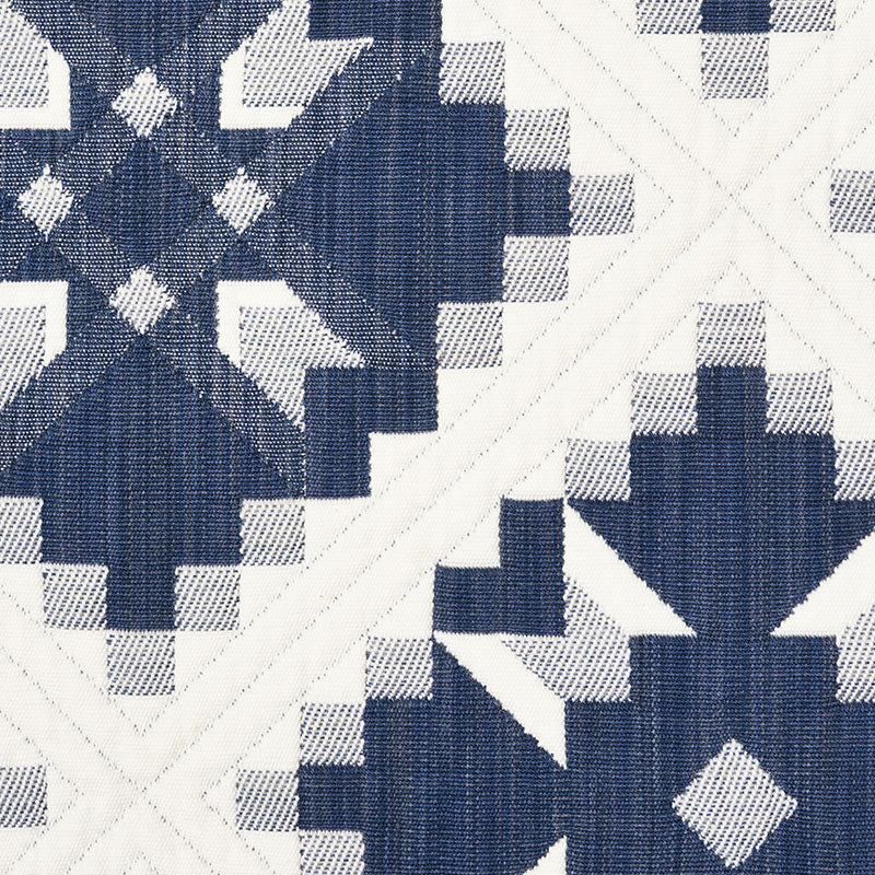 Navy blue and white geometric quilt fabric with star and diamond block designs, woven texture.