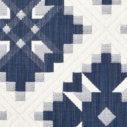 Navy blue and white geometric quilt fabric with star and diamond block designs, woven texture.