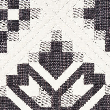 Black and white geometric quilt-block textile with chevrons and a star-like central motif.