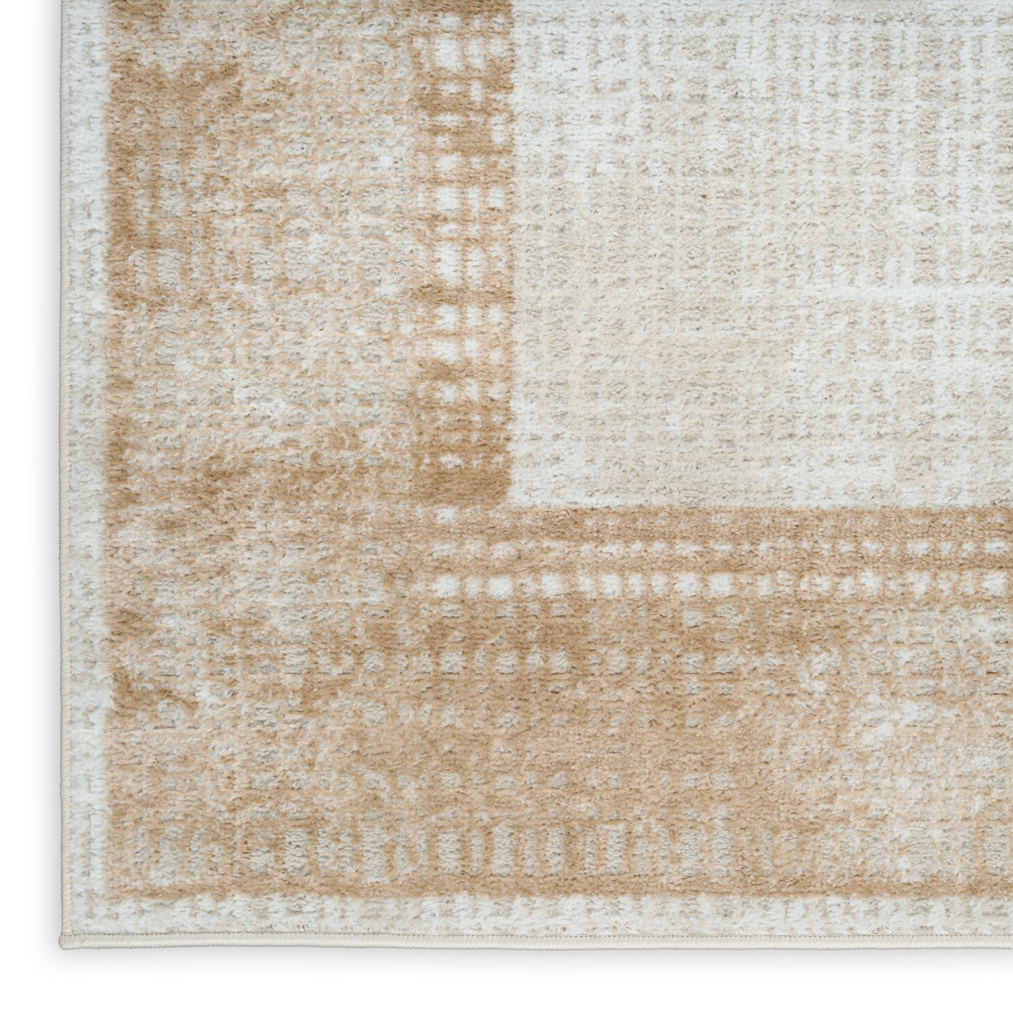 Close-up of beige and tan geometric area rug with textured pile and light border, neutral modern decor.