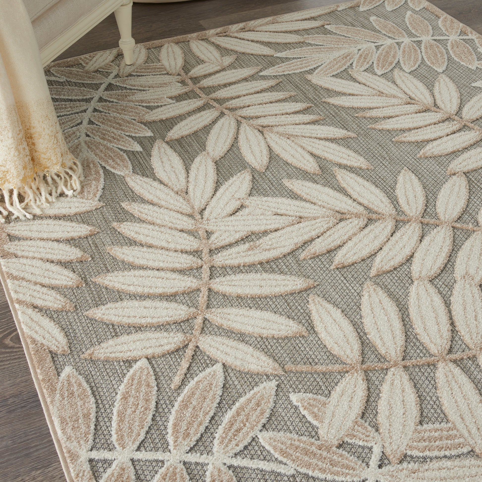 Rectangular textured gray rug with cream botanical leaf pattern and fringed edge.