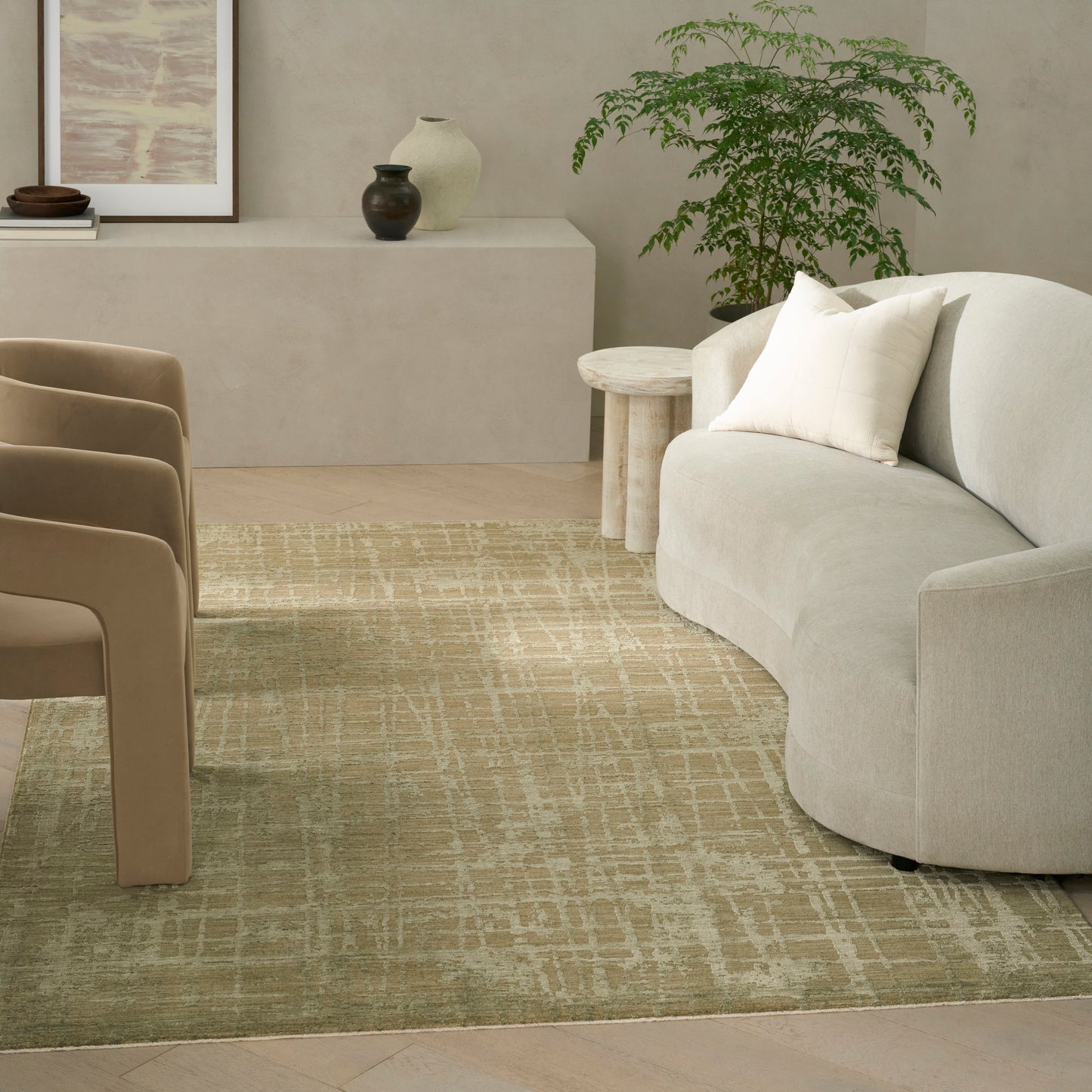 Beige curved sofa with cream cushions, round wood side tables, tan chairs, and a beige patterned rug in a serene living room.