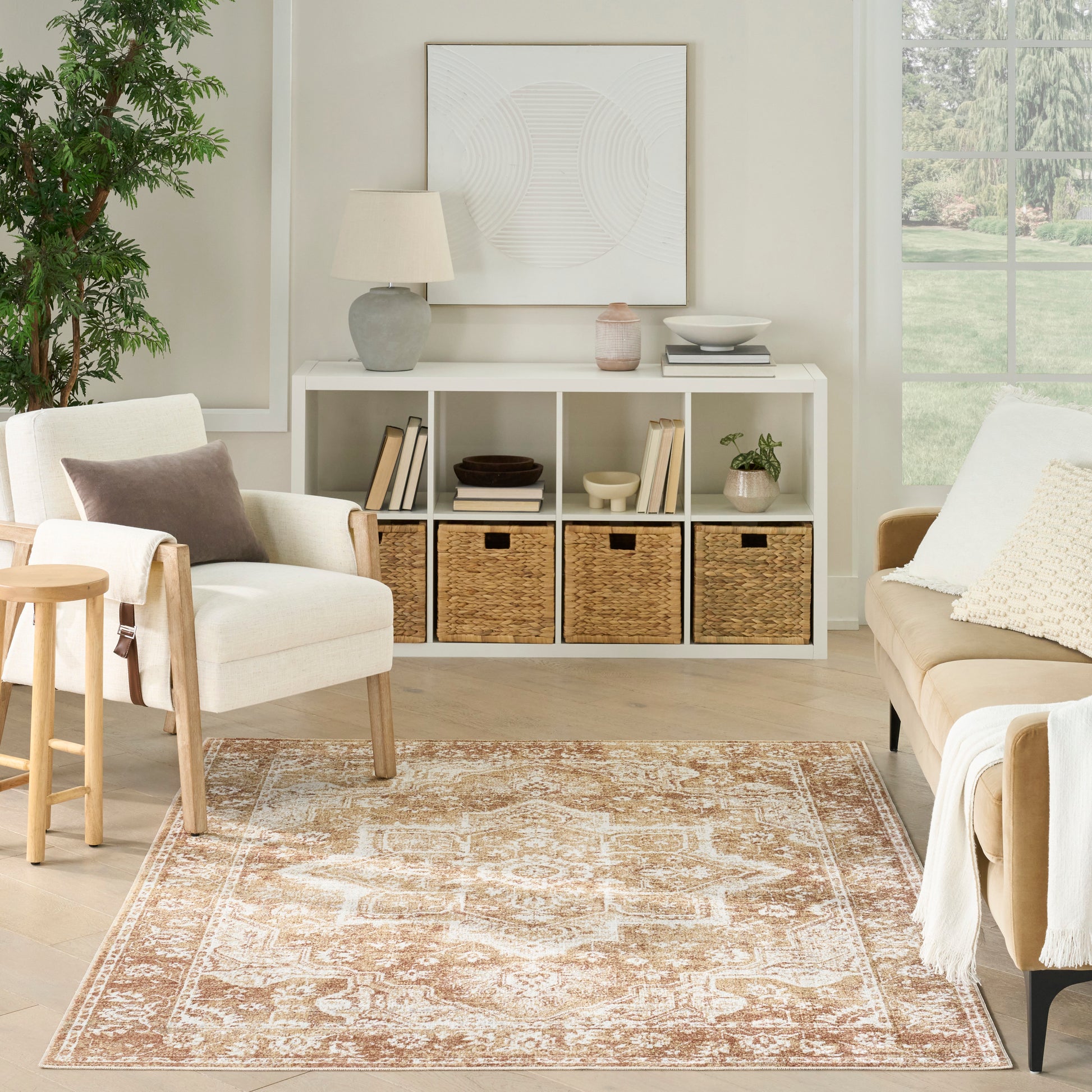 Neutral living room with white cubby storage, woven baskets, sofa and chair, light wood stool, plant, and patterned rug.
