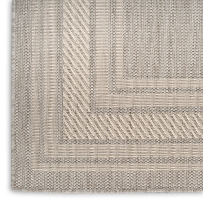 Beige woven area rug close-up with layered borders and textured geometric pattern in taupe tones.