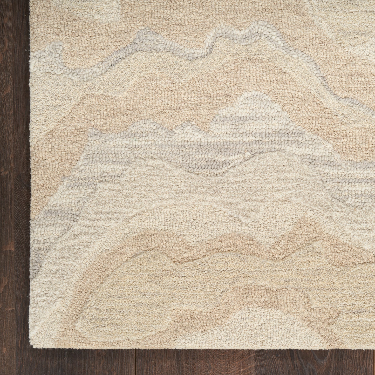Beige and cream abstract wavy rug with textured loop pile on dark wood floor.