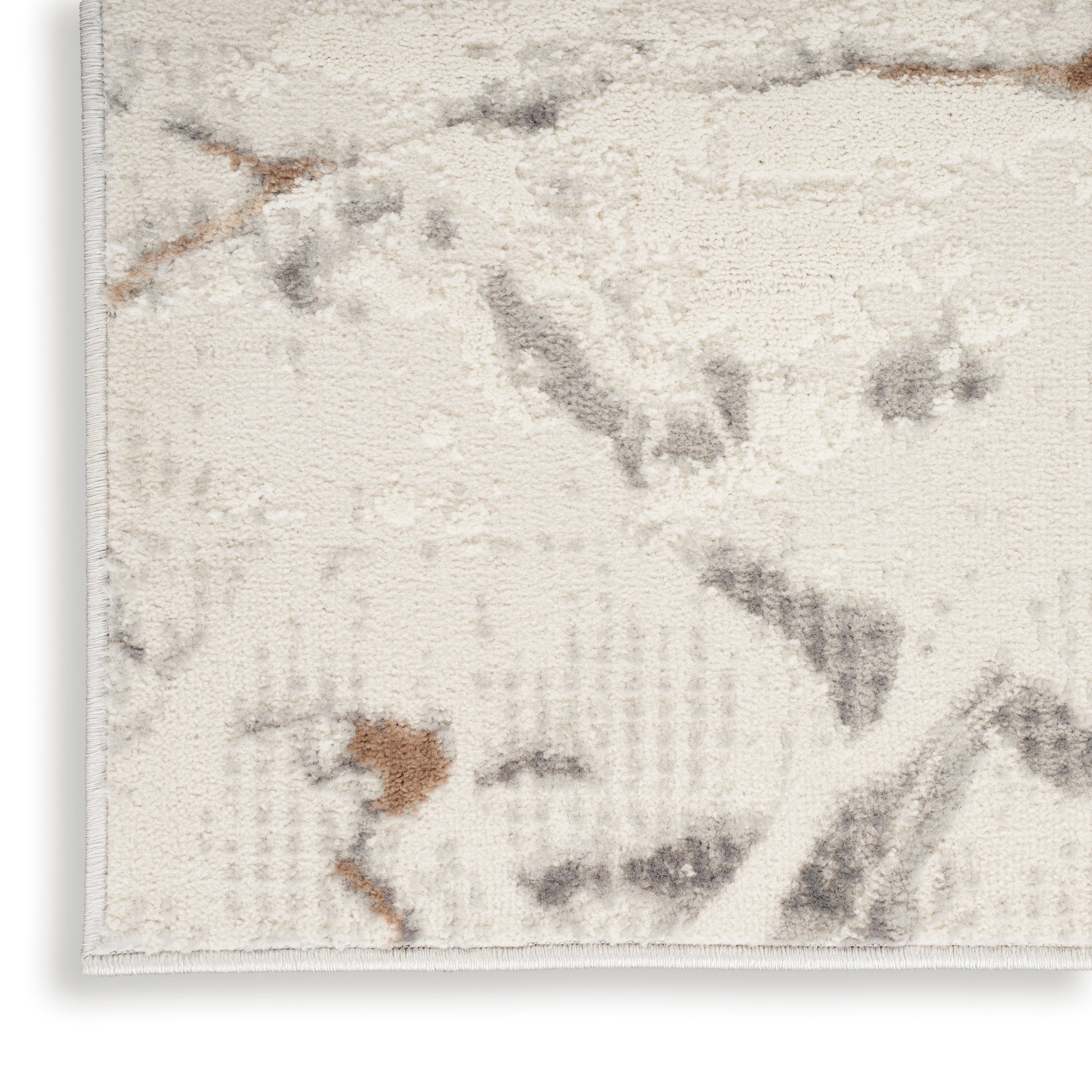 Cream area rug with abstract gray and brown shapes; soft woven texture, rectangular.