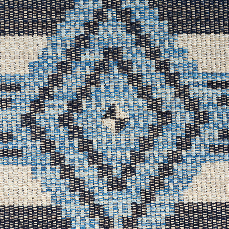 Woven rug with cream background and blue and navy diamond kilim-style pattern; geometric, textured fabric.