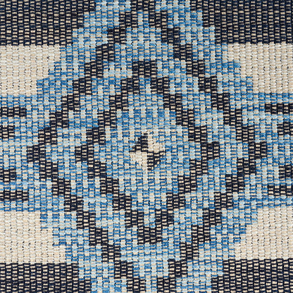 Woven rug with cream background and blue and navy diamond kilim-style pattern; geometric, textured fabric.