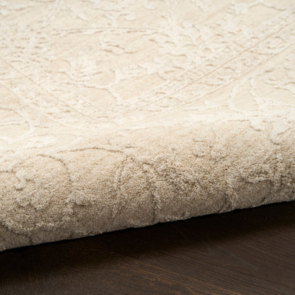 Cream tufted rug with a subtle damask floral pattern and plush pile, rolled edge on dark wood floor.