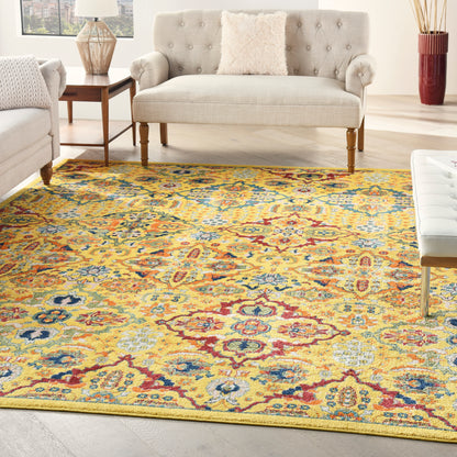 Yellow ornate patterned area rug with blue and red accents in a bright living room with a beige tufted sofa and wooden legs.