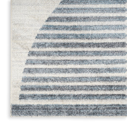 Soft ivory shag rug with blue-gray curved stripes forming arcs; plush, contemporary coastal decor.