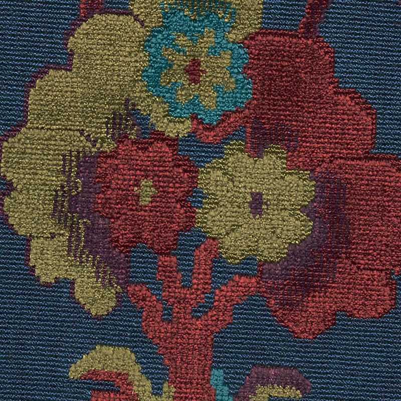 Colorful floral velvet fabric featuring red, yellow and teal blossoms on a blue background; textured.