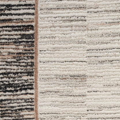 Close-up of a two-toned area rug with a black striped left panel and beige textured right field, shaggy pile.