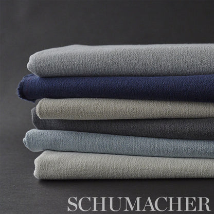 Stack of folded plush terry towels in grey, navy, beige, and blue on a dark backdrop.