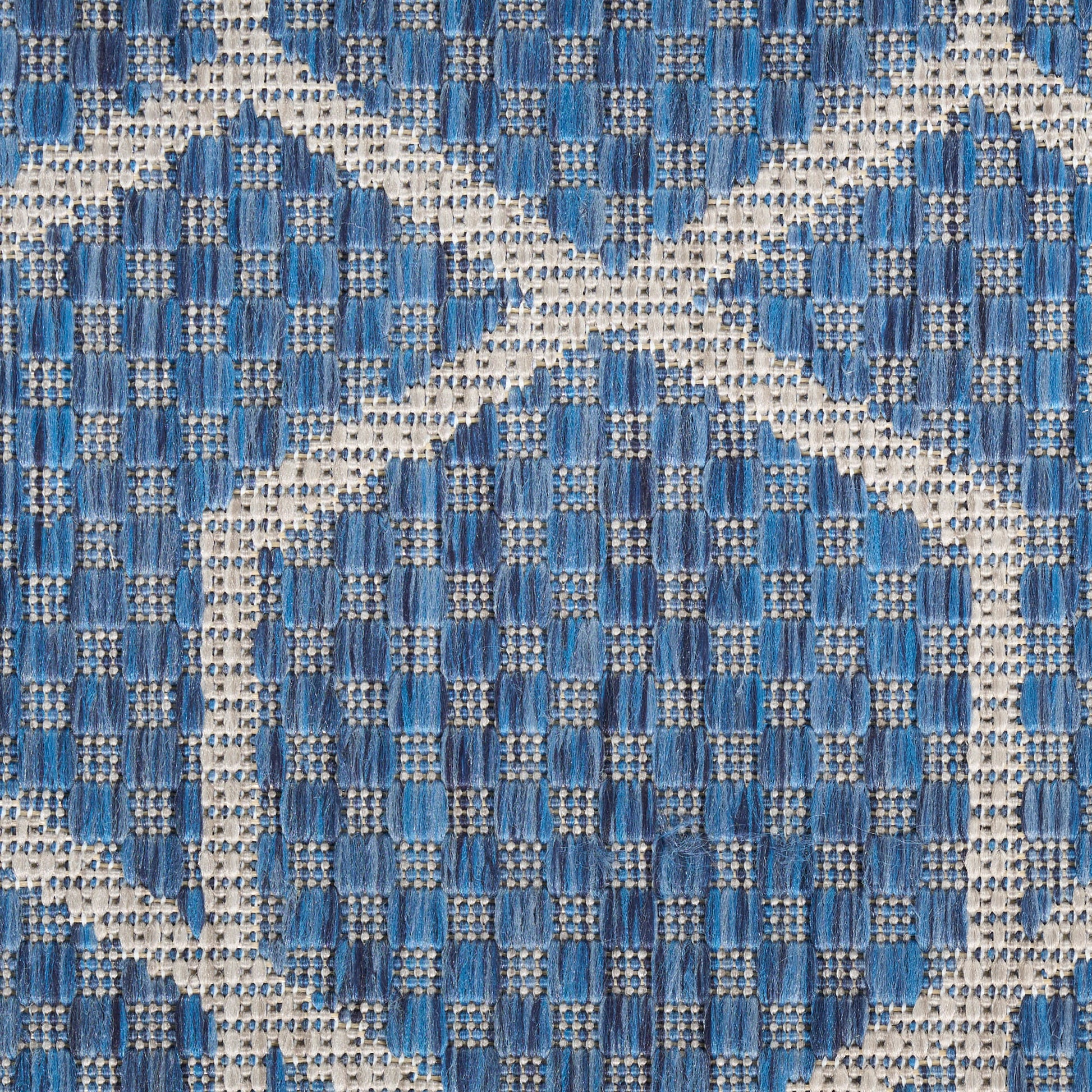 Blue woven fabric with cream diamond-grid pattern and circular medallions in denim blues; textured textile.