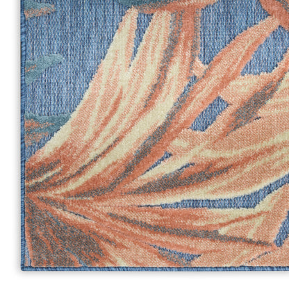 Blue tufted rug with peach tropical leaves and cream highlights; textured pile with a blue bound edge.