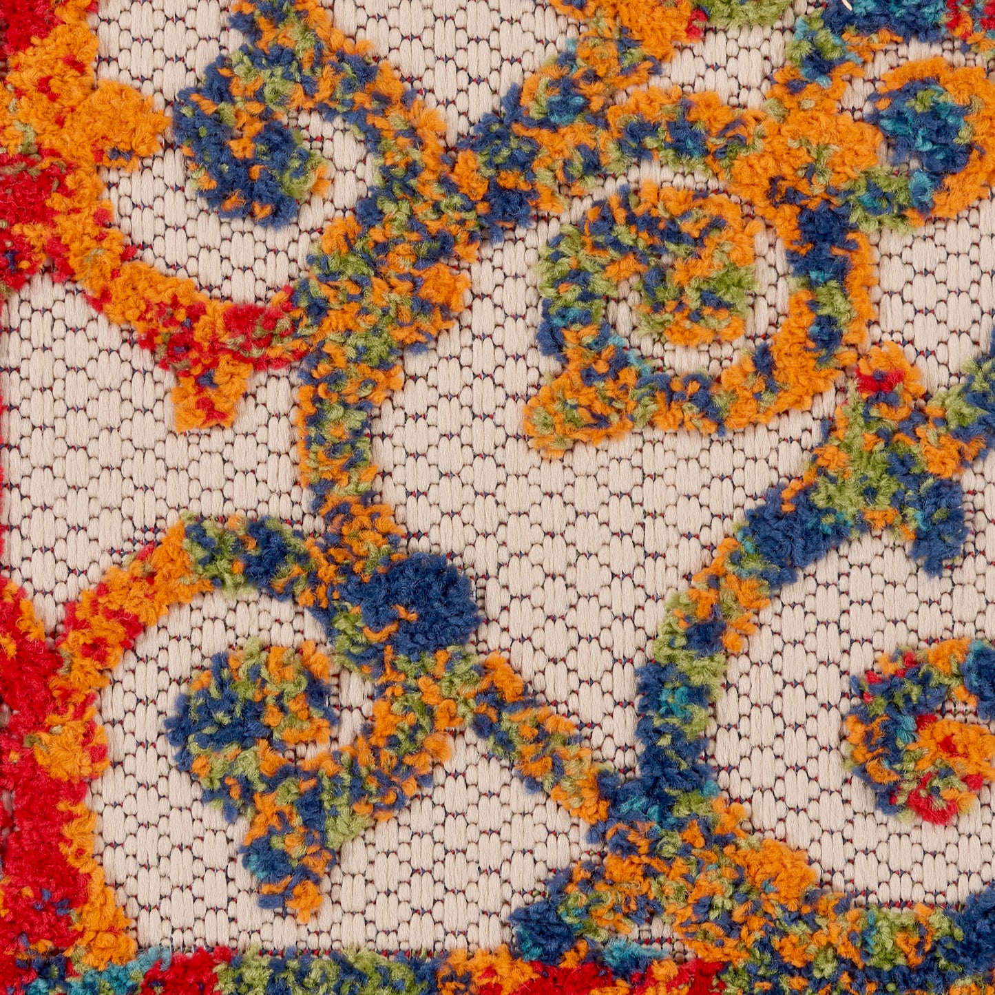 Colorful tufted rug with orange, blue, green and yellow loop rosettes on a beige woven lattice background.
