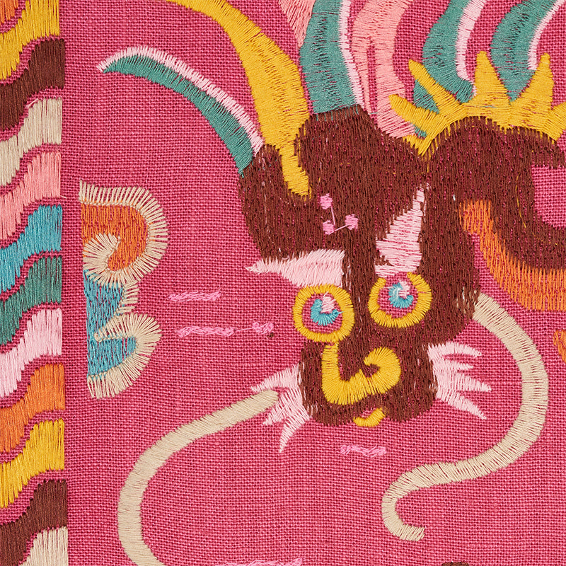 Vibrant pink embroidery of a stylized Lotan dragon with a brown head, yellow horns, turquoise mane, and blue-yellow ears.
