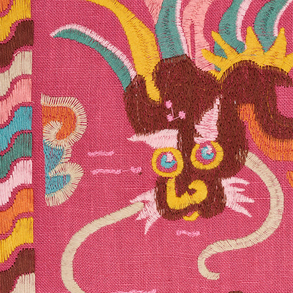 Vibrant pink embroidery of a stylized Lotan dragon with a brown head, yellow horns, turquoise mane, and blue-yellow ears.