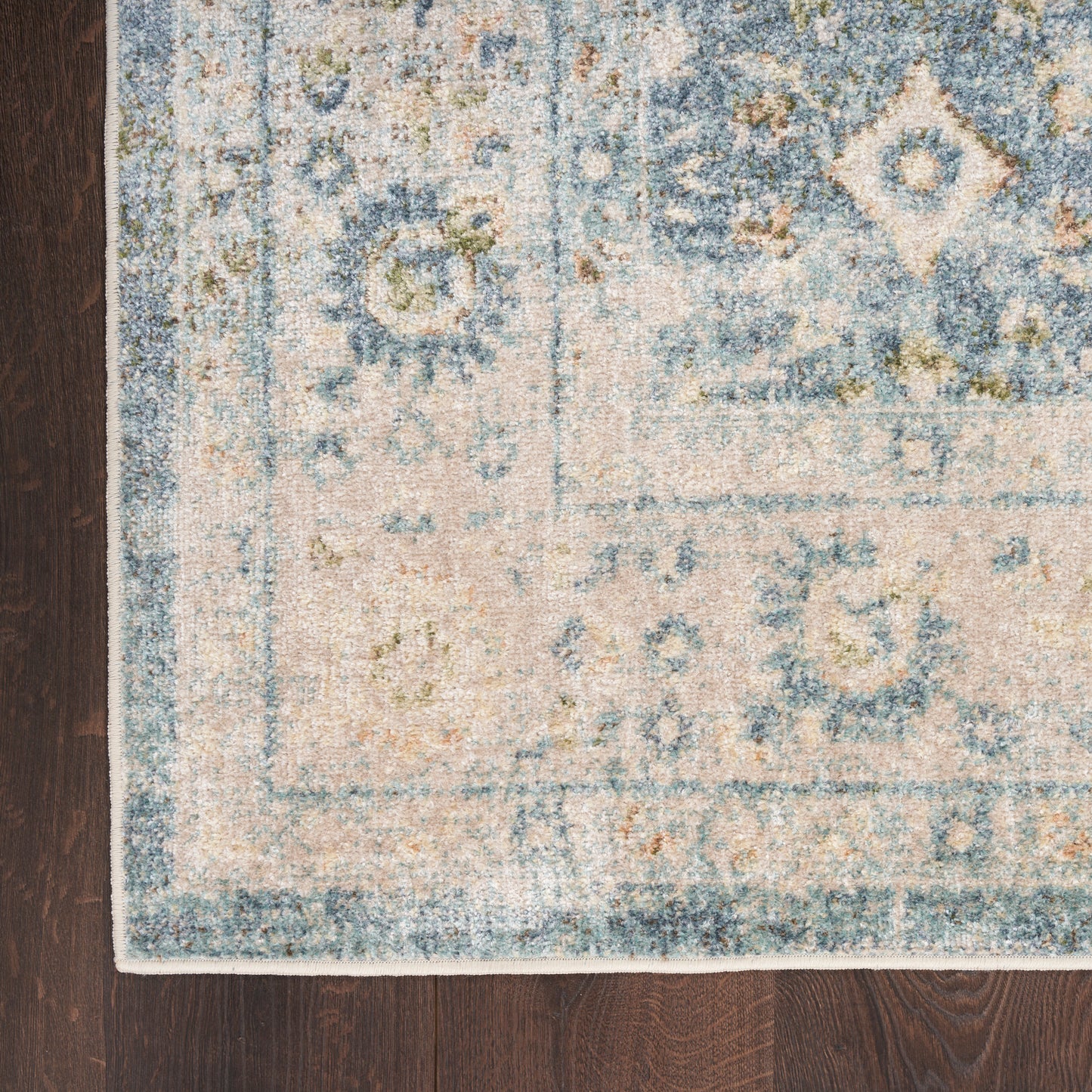 Blue and cream distressed oriental rug with medallion motifs on dark wood floor