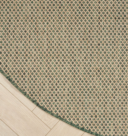 Round woven rug with green border and tiny diamond lattice pattern on light wood floor.
